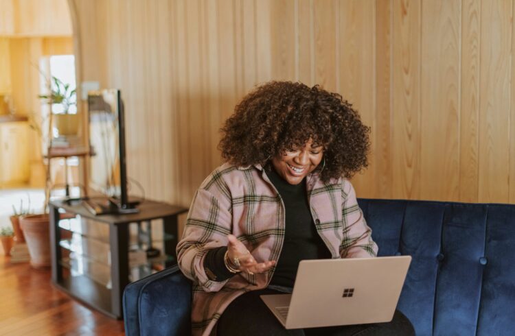 The image shows a black woman on her laptop. The woman is enjoying a video call.